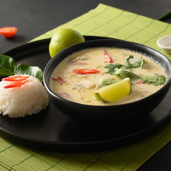 Creamy Tom Kha Gai soup with chicken, lime, and chili, served with white rice.